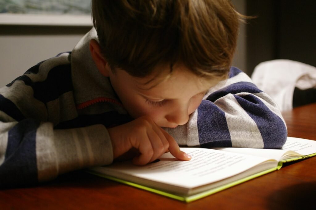 Niño leyendo un libro en una mesa de madera
